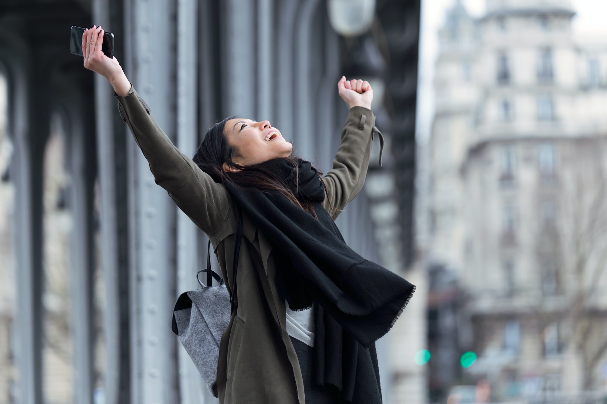 Excited asian young woman celebrating a success in the street.