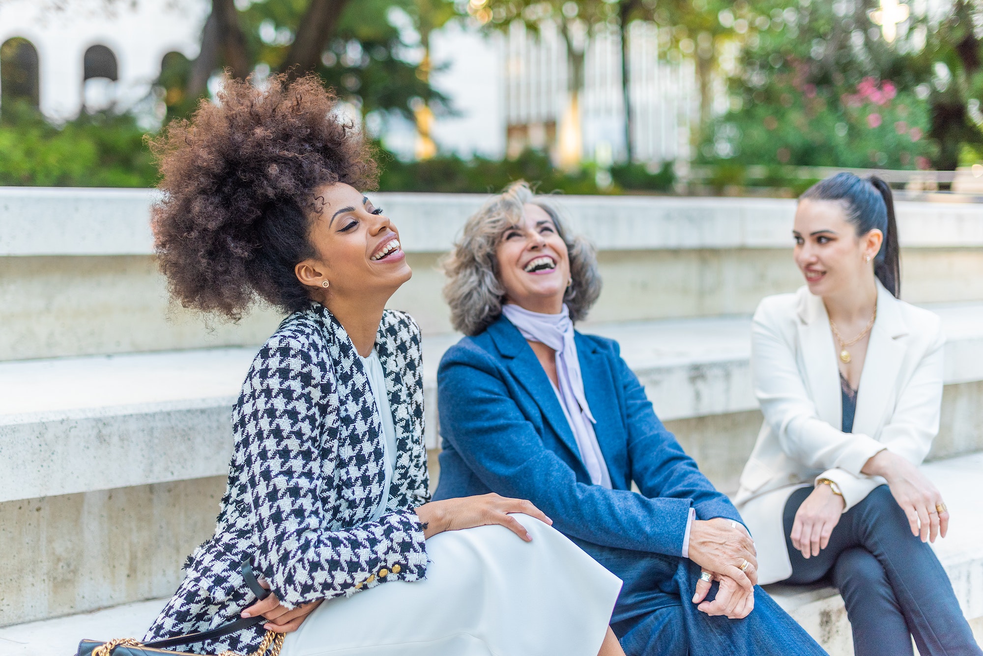 women seated with their legs crossed and dressed in suits
